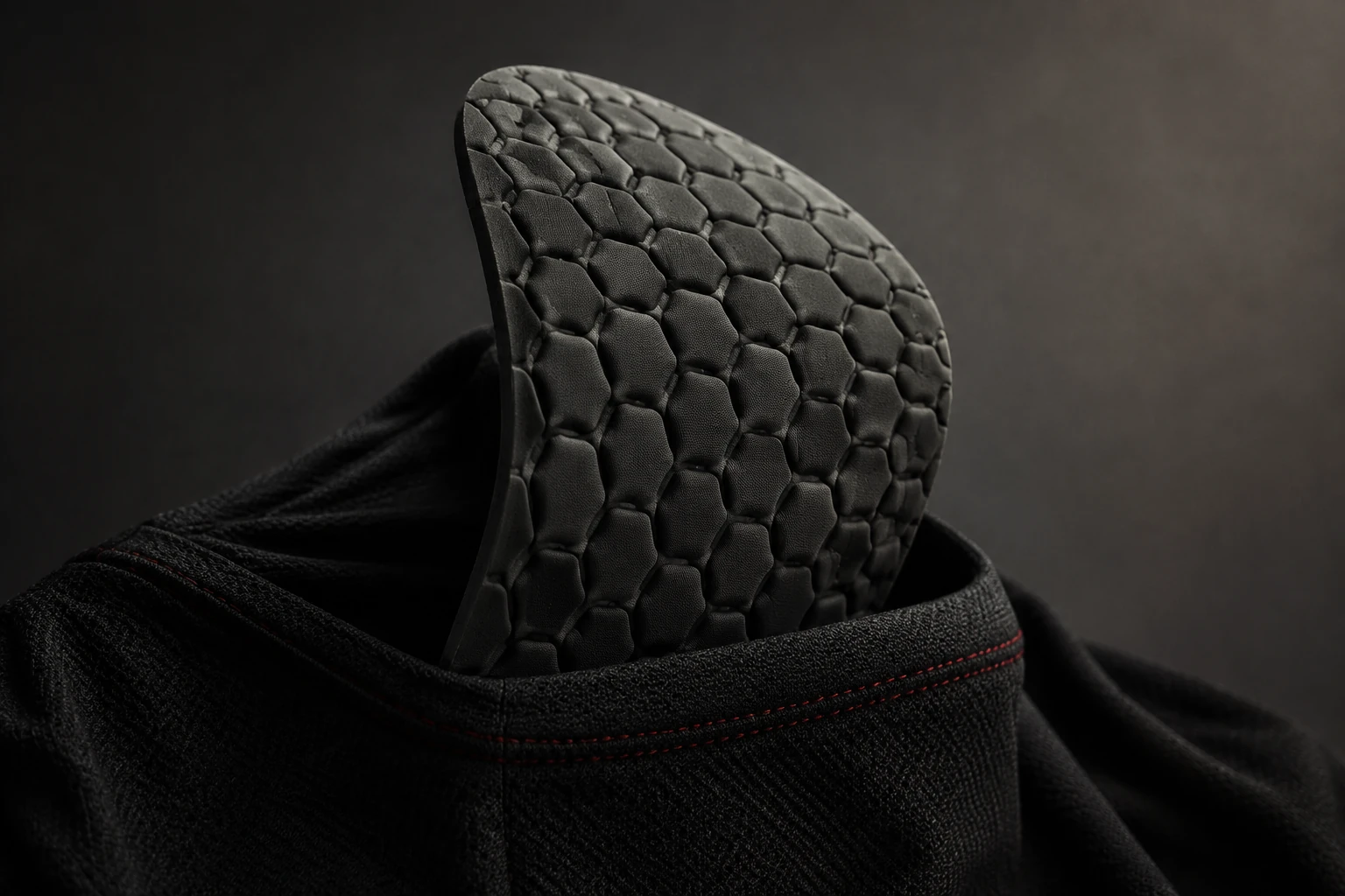 Photorealistic concept study of a flexible cellular protective pad partially exposed inside a black textile pocket