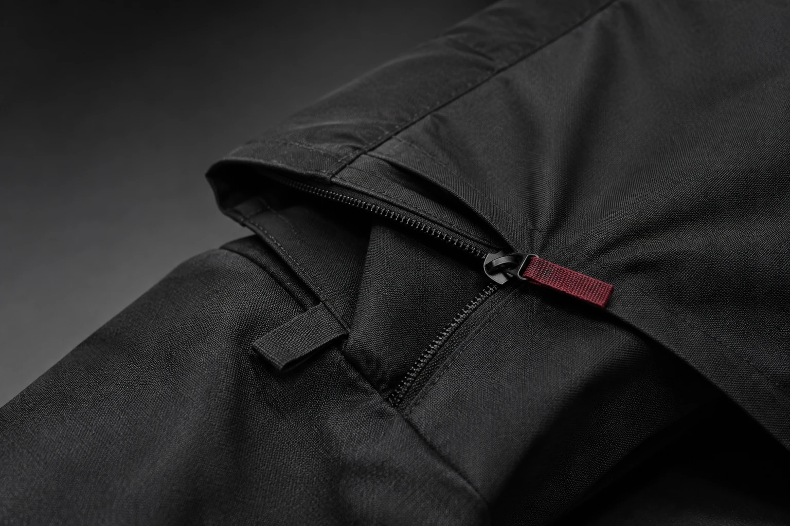 Photorealistic concept study of a detachable graphite garment panel with a concealed zipper and red pull tab