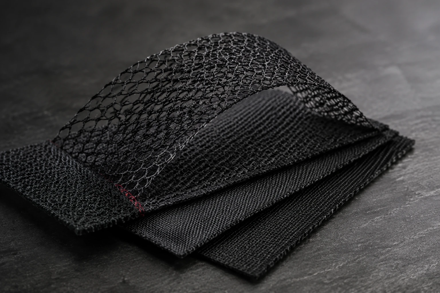 Photorealistic concept study of lightweight black spacer mesh and thin layered textile swatches