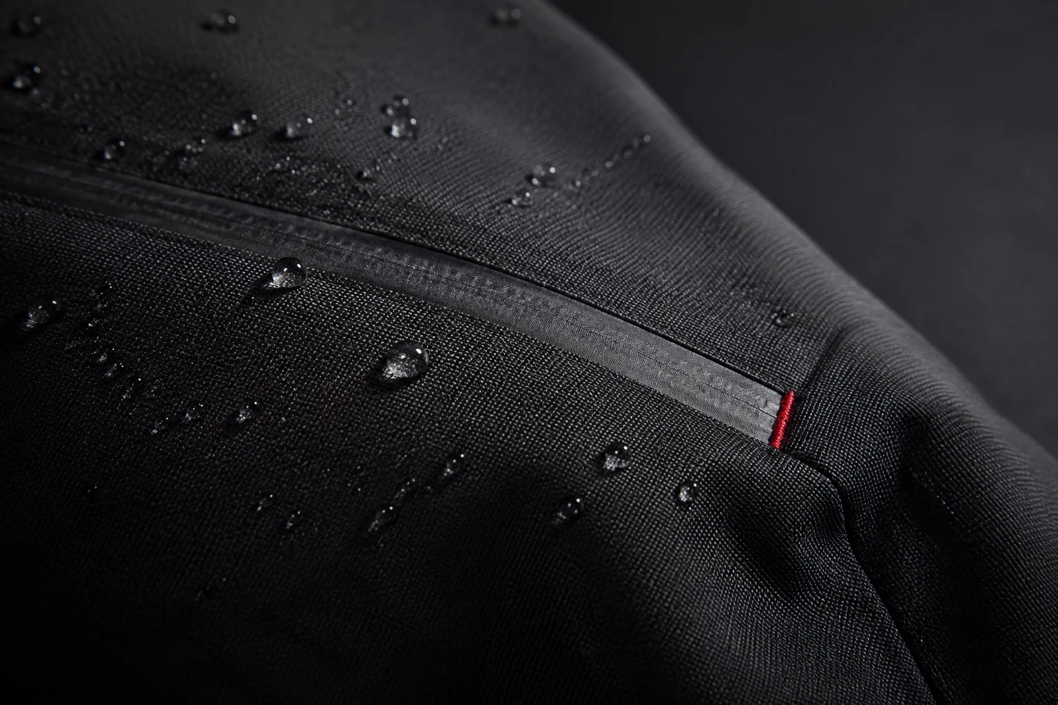 Photorealistic concept study of water droplets on a graphite textile shell with a bonded seam